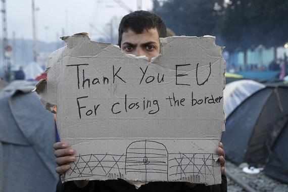 A refugee holds the message "Thank You EU for closing the border” during protest in the border betwe
