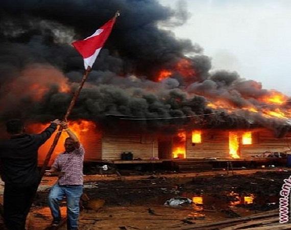 Dua orang melepas tiang bendera di lokasi permukiman warga Gafatar yang dibakar massa di kawasan Mon