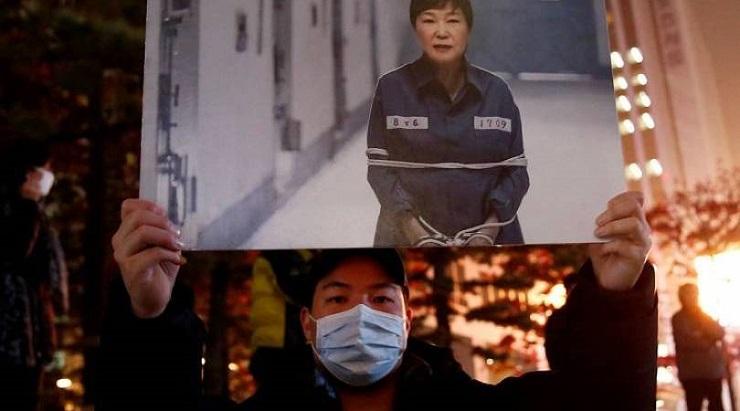 Seorang demonstran membawa poster bergambar rekayasa foto Presiden Korsel Park Geun-hye mengenakan b