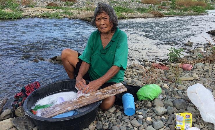 Elisa Hernandez washes clothes on the bank of the Boac river (Photo: Jason Strother)