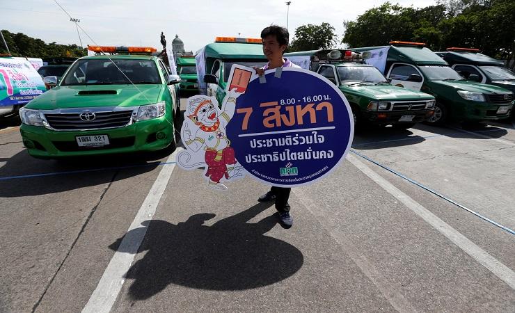 Pekerja Komisi Pemilihan Thailand memegang spanduk selama sebuah acara untuk mempromosikan pengumpul