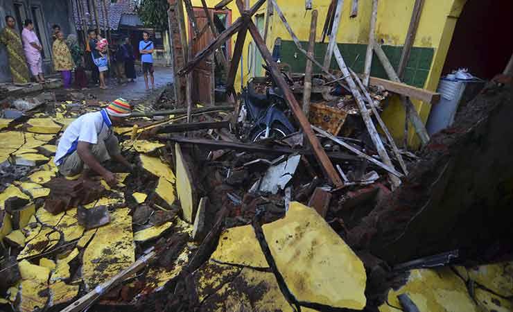 Warga Tasikmalaya membersihkan puing rumahnya akibat gempa.