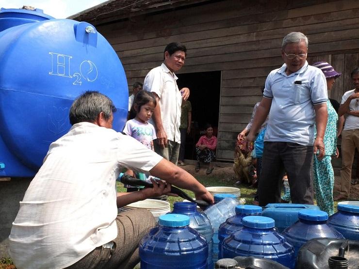 Outside the community hall vessels are filled with donated water for locals who are on the ID Poor e