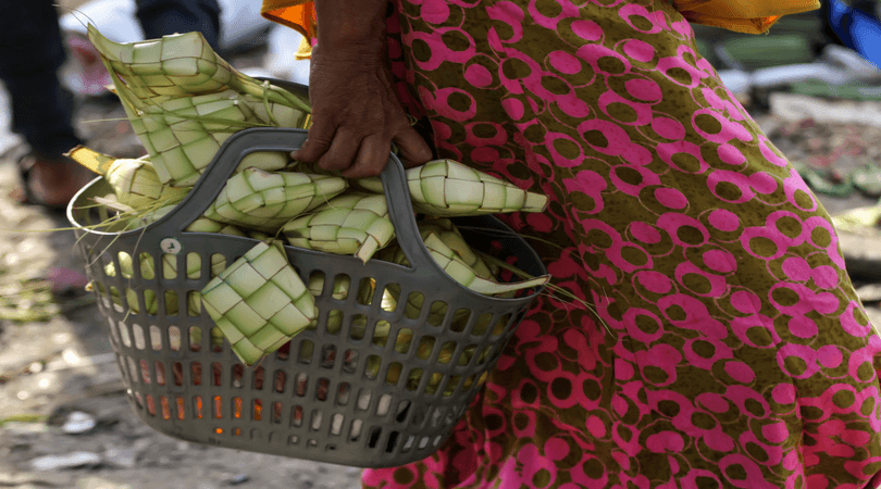Seorang warga membawa pulang bungkus ketupat yang dibelinya di pasar tradisional Lhokseumawe, Aceh, 