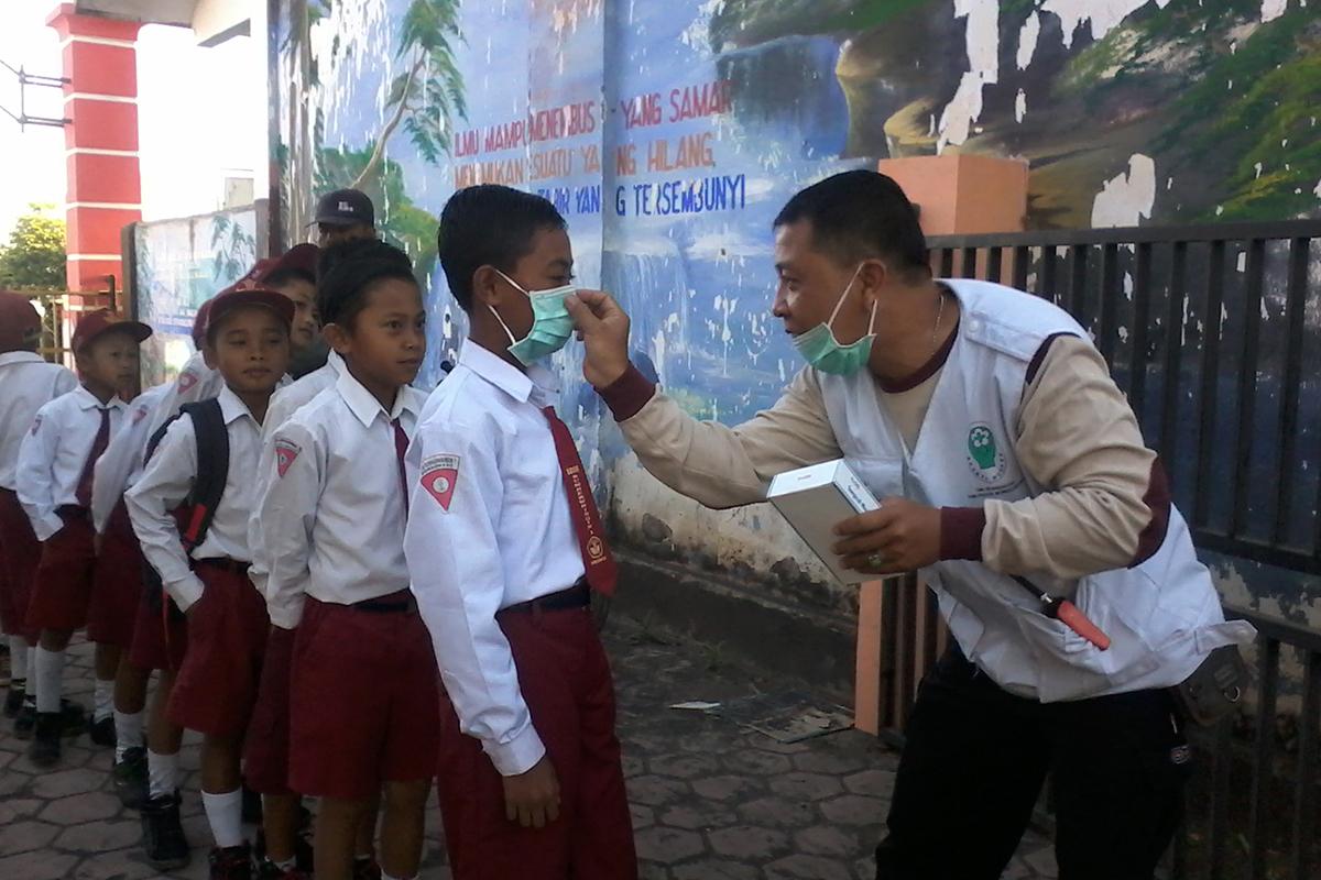 Petugas puskesmas membagikan masker kepada siswa sekolah dasar di SDN Sumber Wringin 1, Bondowoso, J