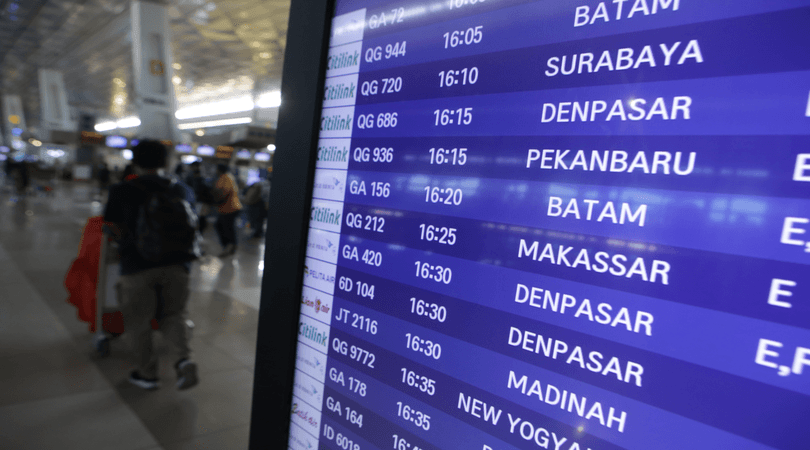 Sejumlah calon penumpang pesawat berjalan di dekat papan informasi penerbangan di Terminal 3 Bandara