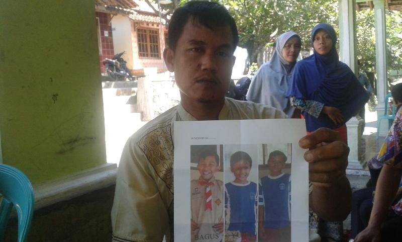 Sutopo, ayah Bagus Susilo (10) menunjukkan foto tiga anak yang tewas tenggelam di Sungai Pasir, Wang