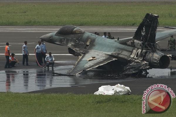 Petugas menyiramkan cairan ke badan pesawat tempur F16 yang terbakar di ujung landasan pacu Pangkala