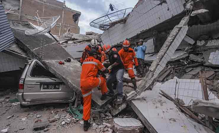Petugas Basarnas membawa korban selamat gempa dan tsunami yang terjebak di dalam puing restoran di P